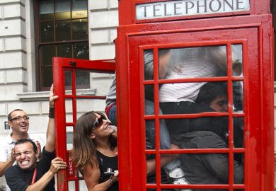 People squeezing in to a telephone box, illustrating class size increases.