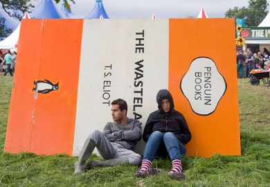 People sitting against a giant book cover of The Wasteland by T.S. Eliot. To illustrate that the number of academics working in under-fire departments such as English and modern languages in UK universities fell to a record low last year.