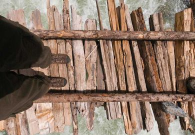 Person crossing river on wooden bridge