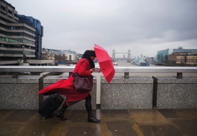 woman with umbrella walking across bridge, London
