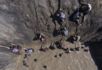 Participants climb up a wall during the Race of Heroes obstacle course event.