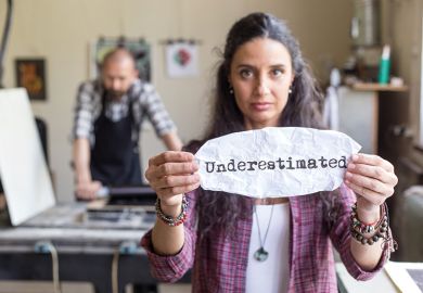 Young female lithography worker holding a sign "underestimated"