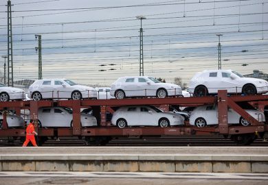 New Audi AG automobiles, manufactured by Volkswagen AG, sit under protective covers on a railway transporter beside a platform at Ingolstadt central train station in Ingolstadt, Germany