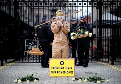 A protester from the group "Pause The System" stands beside the entrance to Downing Street in central London on March 17, 2020.