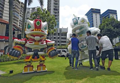 Workers carry a robot anime figure depicting the mask of a lion dance named "Lunar Guardians" in an outdoor installation at the Sun Yat Sen Nanyang Memorial Hall in Singapore