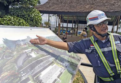 A worker shows an artist rendition of the country's new capital Nusantara to illustrate Doubts over higher education vision for Indonesia’s new capital