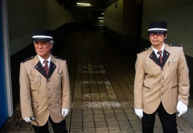 Tokyo, Japan - October 24, 2018 Local security guards in matching tan suits stand outside of a parking garage in Tokyo’s Shibuya district.