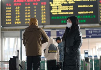 A Chinese traveller at a railway station A traveller in a face mask at a railway station in Suzhou, China, illustrating the downturn in Chinese international students post-Covid