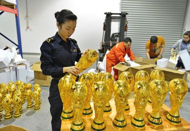 A woman standing over a box of football trophies