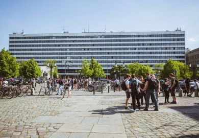 A large rectangular building with several students and bikes near it 