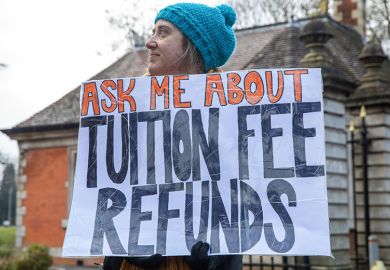 A university staff member from the University and College Union (UCU) stands holding a sign stating "ask me about tuition fee refunds" at an official picket outside Royal Holloway University of London on the first day of strike action, 9 February, 2023.