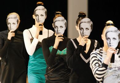 Models displaying cut out masks of former model 'Twiggy' parade outfits by Australian designers