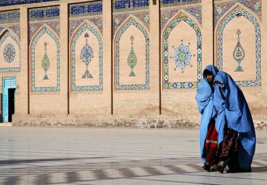 Two women walk in front of the Great Mosque of Herat in Herat, Afghanistan