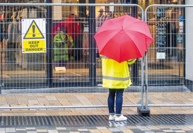 Someone with an umbrella stands by a barrier