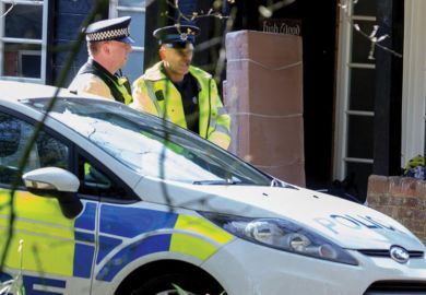 United Kingdom policemen standing by patrol car
