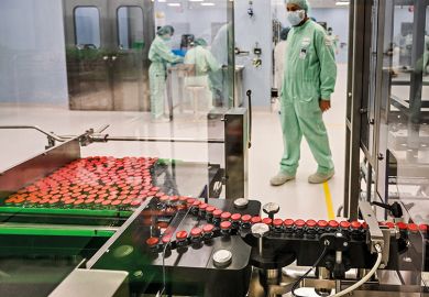 A laboratory technician supervises capped vials during filling and packaging tests of a Covid-19 vaccine candidate, 2020