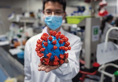 Scientist with model of coronavirus