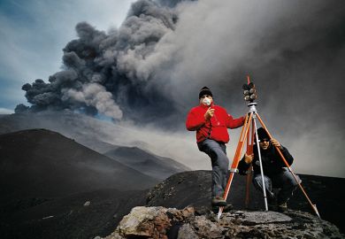 Geologists stand before an eruption on Mt. Etna in November 2002, and take readings