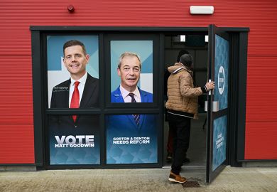 A person walks through a doorway printed with the faces of Reform UK candidate Matt Goodwin and Reform UK leader Nigel Farage during an event ahead of the February 26 Gorton and Denton by-election, in Denton, northwest England on 5 February, 2026. 