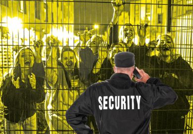 Security guard in front of fence with crowd smiling people behind