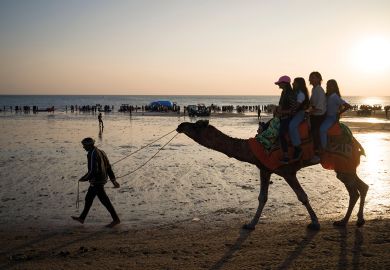 Tourists ride a camel on a beachfront in Mandvi in Gujarat, India to illustrate Coventry among India branch campus contenders