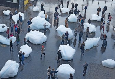 Visitors interact with blocks of melting ice from an exhibit outside Tate Modern in central London to illustrate A measure of reality