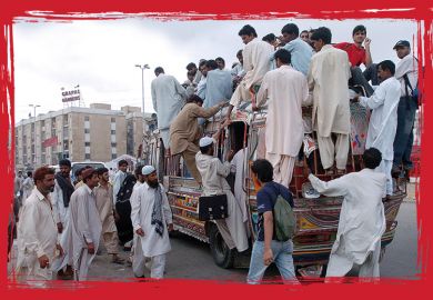 Pakistani commuters climb on a crowded public transport vehicle in Karachi, to illustrate 'State of emergency'