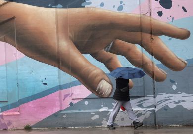 Wall art of hand reaching out with person walking by holding an umbrella in Toronto to illustrate How to meet  students’ soaring mental health  needs on a budget