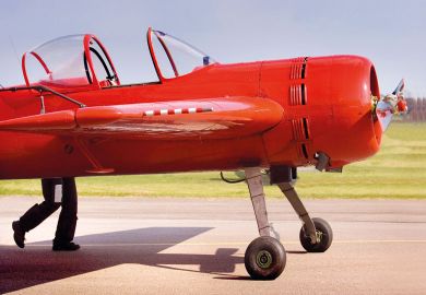 A bright red plane appears to have legs, as a pilot pushes his aircraft to illustrate UK funding council budgets set to drop