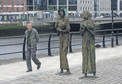 Man walking past the famine remembrance statues in Dublin