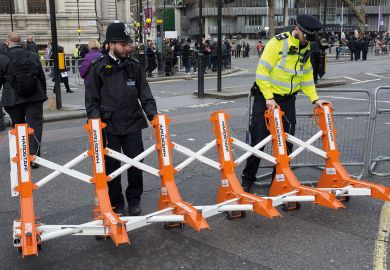 Met police officers drag barriers  into place to illustrate opposition in Whitehall to Home Office plan for graduate visa limits