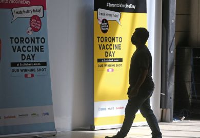 Person walks by Toronto Vaccine Day poster Person walks by Toronto Vaccine Day poster as metaphor for Canadian universities finally move to mandate vaccines