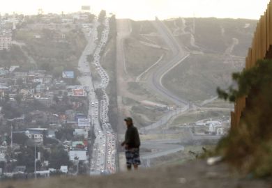 A man walks on the Mexican side of the U.S.-Mexico border barrier 