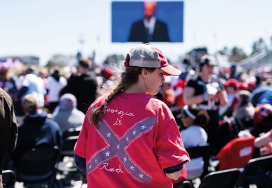 An attendee wears a Confederate battle flag shirt with 'Georgia is Red" written on it to illustrate Campus diversity rule fails in US southern states