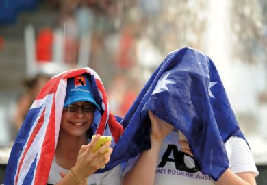 Spectators uses a flag to cover as rain stops play at the Australian Open tennis championship in Melbourne to illustrate delays