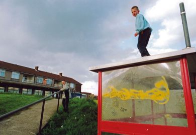 Boys playing on bus shelter on run down council estate; Bradford UK to illustrate social mobility