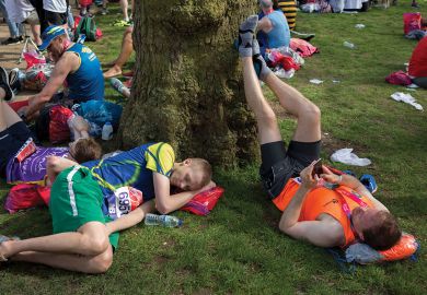Tired long-distance runners rest after finishing the London Marathon to illustrate people are deep tired