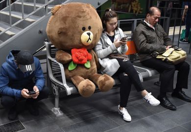 Commuters use their mobile phones next to a giant soft toy bear to illustrate New grant delays hit Australian researchers 