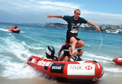 Eddie Irvine of Northern Ireland jumps from a IRB rescue boat onto Bondi Beach, Sydney to illustrate Australian universities redraw casual employment as law comes in
