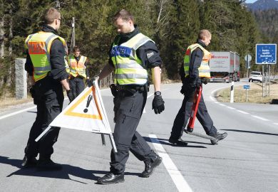 German police guards secure an access road to illustrate Language barrier holds back international academics in Germany