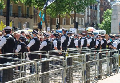  Police standing along a line barriers outside Downing Street as a metaphor for  a Peer sniffs ‘real chance’ of success on UK contract cheating law