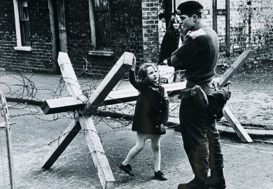 A young girl talking to a British soldier manning a roadblock on a street in Belfast, Northern Ireland during The Troubles, summer 1973