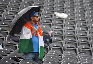 A fan shelters from the rain with an umbrella amongst empty seats as play is delayed during the Semi-Final match of the ICC Cricket World Cup 2019 between India and New Zealand to illustrate ‘Tough year’ for UK international student recruitment