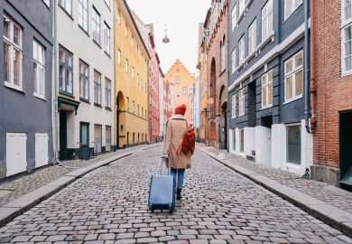 A woman walking down the street and pulling a suitcase to illustrate wanting to leave 