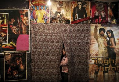 An Indian worker waits for customers as he is surrounded by Bollywood film posters at a small cinema in New Delhi to illustrate India’s JNU target for Bollywood film and ‘jingoistic nationalism’