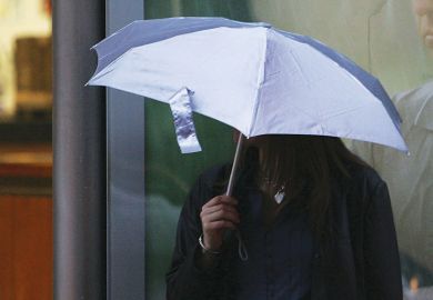 Woman holding umbrella over her head to illustrate Afghan Chevening scholars ‘let down’ by UK universities