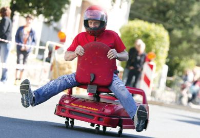 Man racing on an office chair to illustrate Universities must go hybrid to stay relevant, says Coursera CEO
