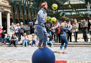 Street performer entertaining people balancing on a ball  in Covent Garden Piazza to illustrate Russell Group draws majority of fee income from overseas
