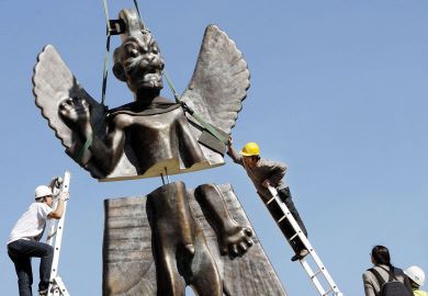 Workmen install a 6-metre fibre glass statue of the god Pazuzu onto the rooftop of the Institute of the Contemporary Arts to illustrate Science degrees ‘unwelcoming’ to religious students