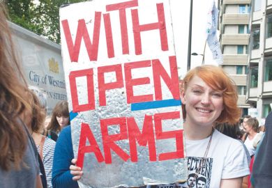 Person in a refugee demonstration London UK holding a banner reading 'With Open Arms'